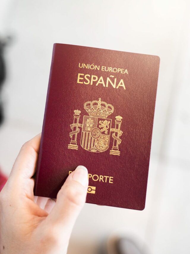 close-up-unrecognizable-female-hand-holds-spanish-european-passport-with-unfocused-luggage-on-background-sunlight-and-flares-travel-concept